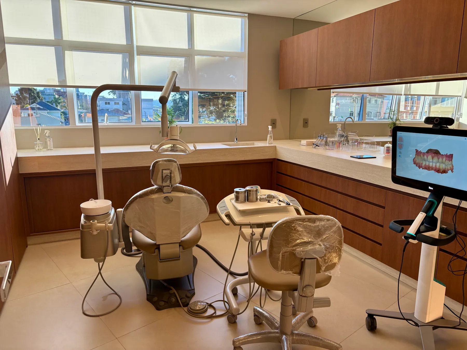 Consultório da Dra. Roberta Gevaerd, com cadeira odontológica, bancada de madeira e scanner intraoral ao lado.